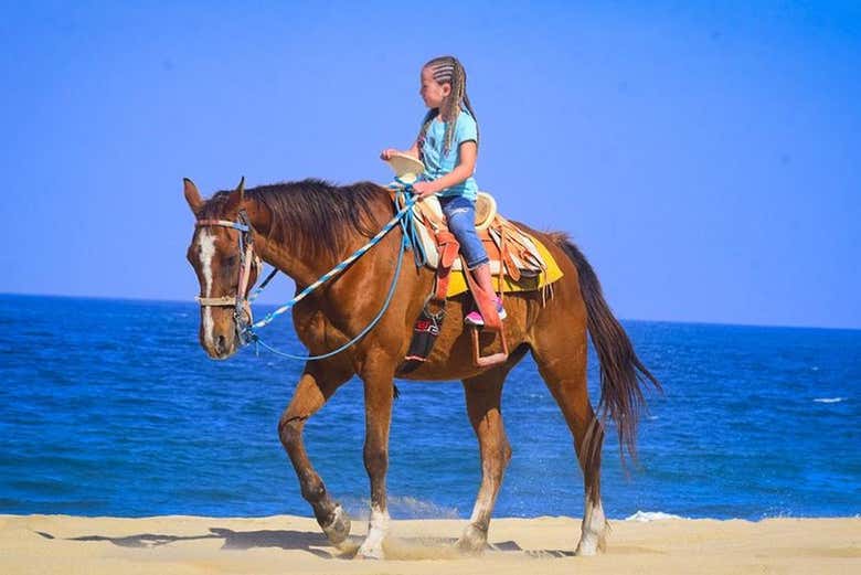 Criança cavalgando pela praia Bonfil
