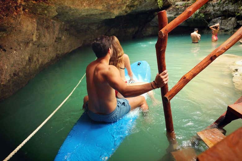 Entering the cenote on a surfboard