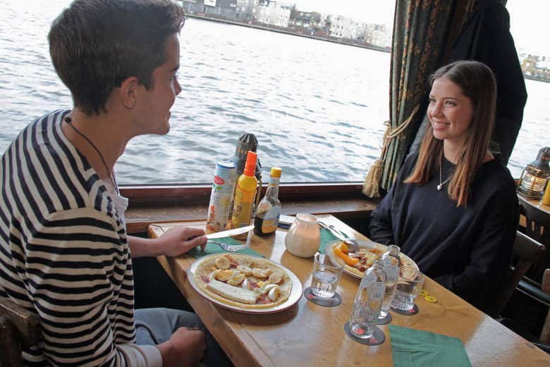 Comendo panquecas doces no barco por Amsterdam