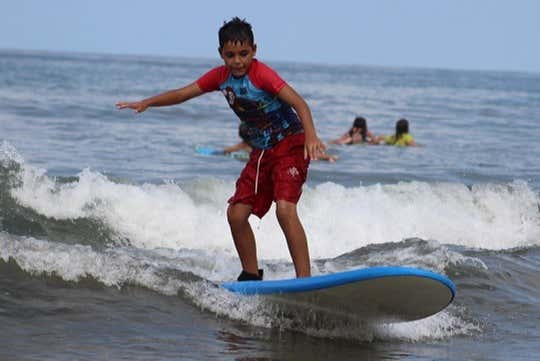 Criança desfrutando da aula de surfe