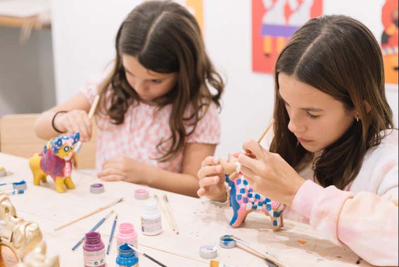 Dos niñas pintando toritos de Pucará