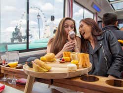 Two friends enjoy snacks with the London Eye in the background