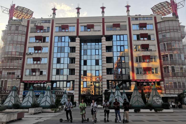 El grupo con los patinetes ante un edificio brutalista
