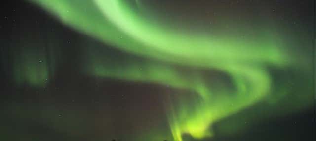 Paseo en moto de nieve bajo la aurora boreal