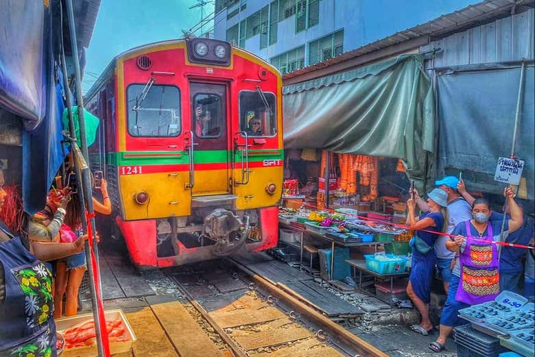 See trains pass through a bustling market