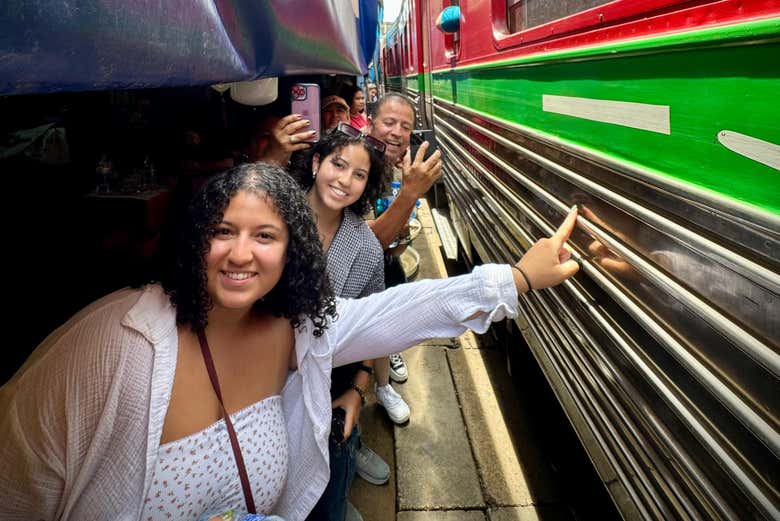 Tocando el tren que recorre el mercado sobre la vía de Mae Klong