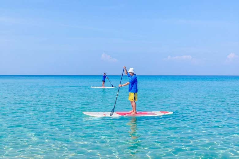 Un hombre remando en paddle surf por las aguas cristalinas