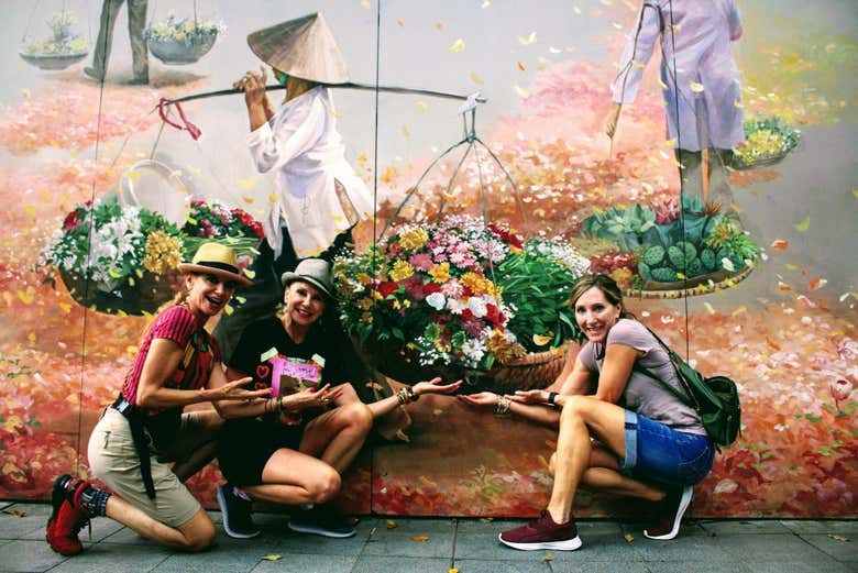 Turistas posando frente a un mural de Hanói