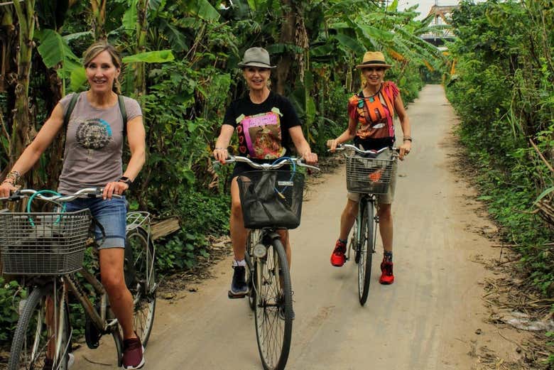 Mujeres pedaleando por un campo de las afueras de Hanói
